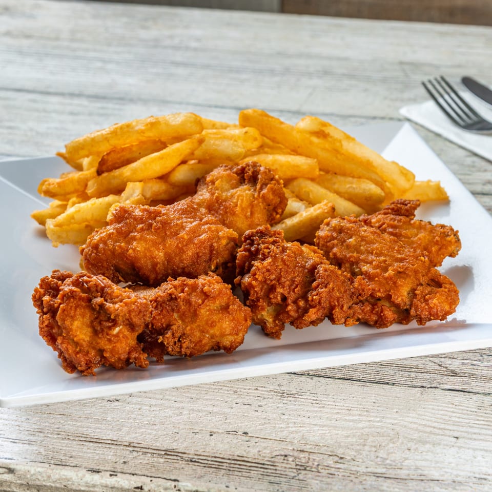 Crispy fried chicken tenders and golden french fries on a white rectangular plate.
