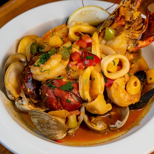 A vibrant Latin-American seafood dish with lobster, shrimp, calamari, and clams in a rich sauce.