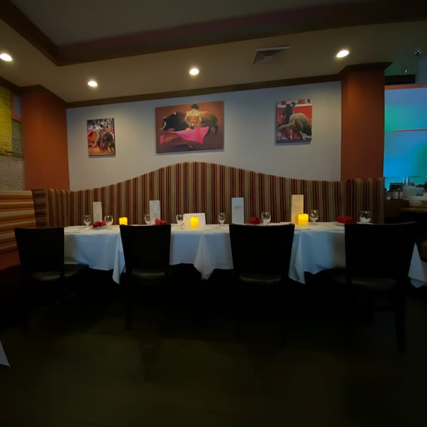 A long dining table set with white tablecloths, candles, and place settings in Sangria Cafe.
