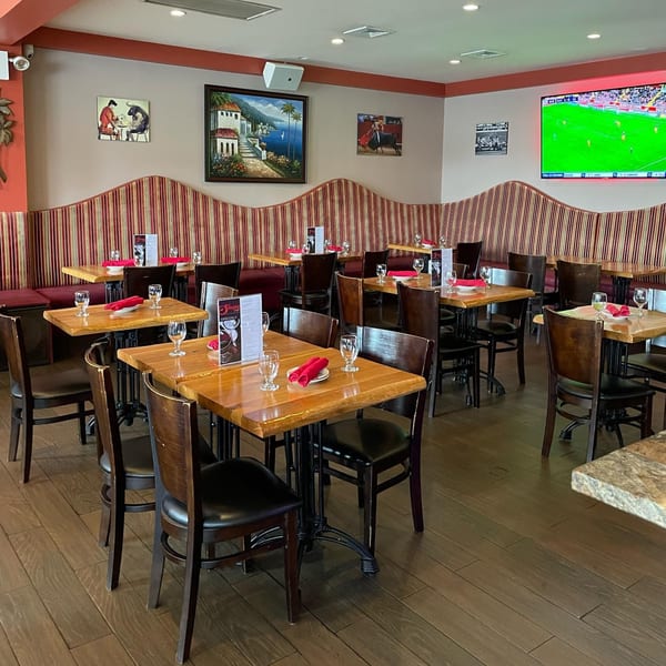 Interior of Sangria Cafe with wooden tables, dark chairs, striped booths, and Latin-inspired artwork.